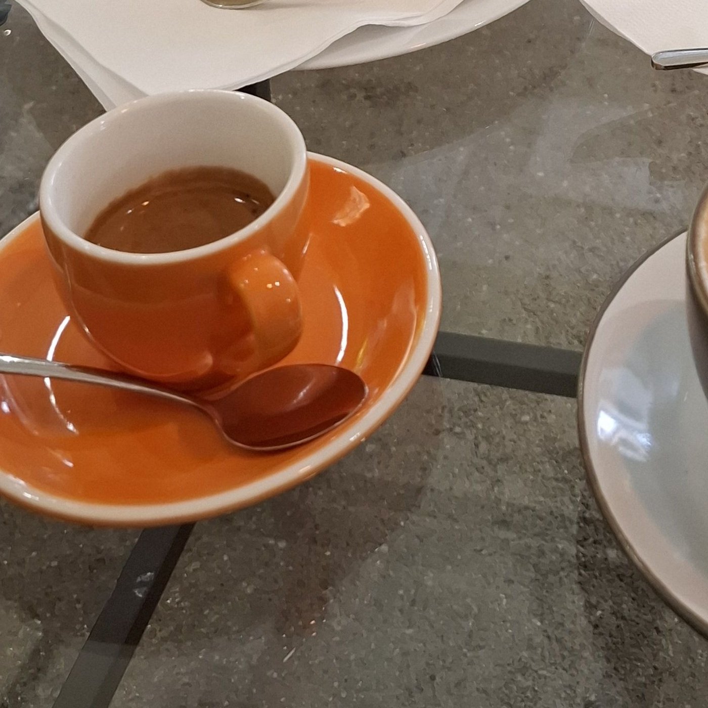 Espresso v oranžovém šálku na skleněném stolku