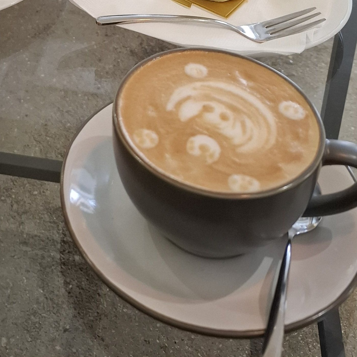 Cappuccino s latte artem medvídka v tmavém šálku